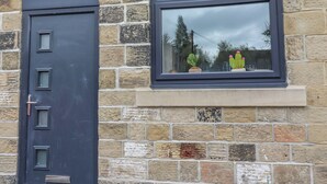 A stone wall with a window displaying two potted cacti. - Eden Cottage (Keighley)