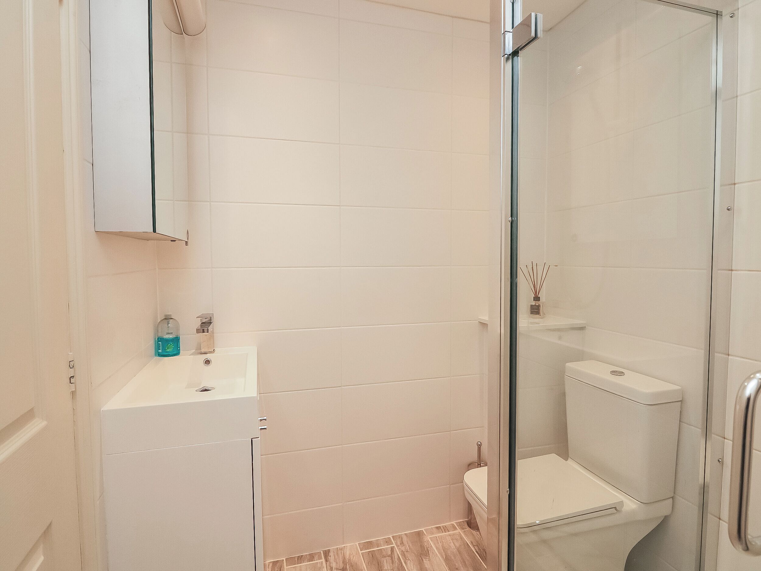 A bathroom with a glass shower enclosure, a white sink, and a toilet.