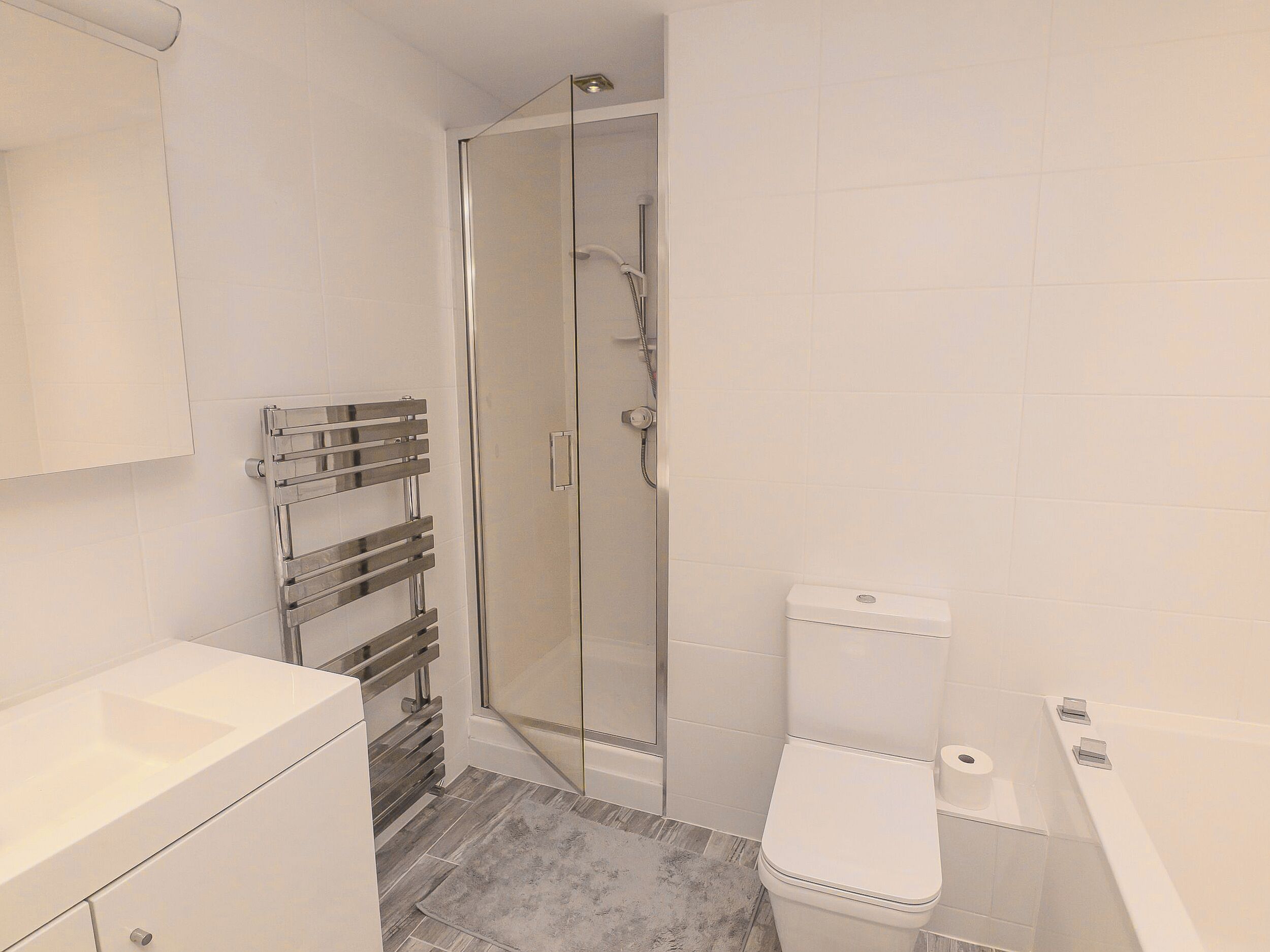 A modern bathroom with a glass shower enclosure, a white toilet, and a built-in sink.