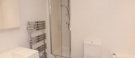 A modern bathroom with a glass shower enclosure, a white toilet, and a built-in sink.