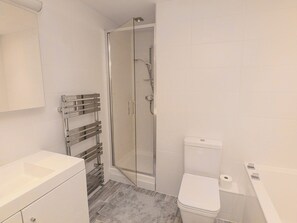 A modern bathroom with a glass shower enclosure, a white toilet, and a built-in sink. - 22 Bolt Head (Salcombe)