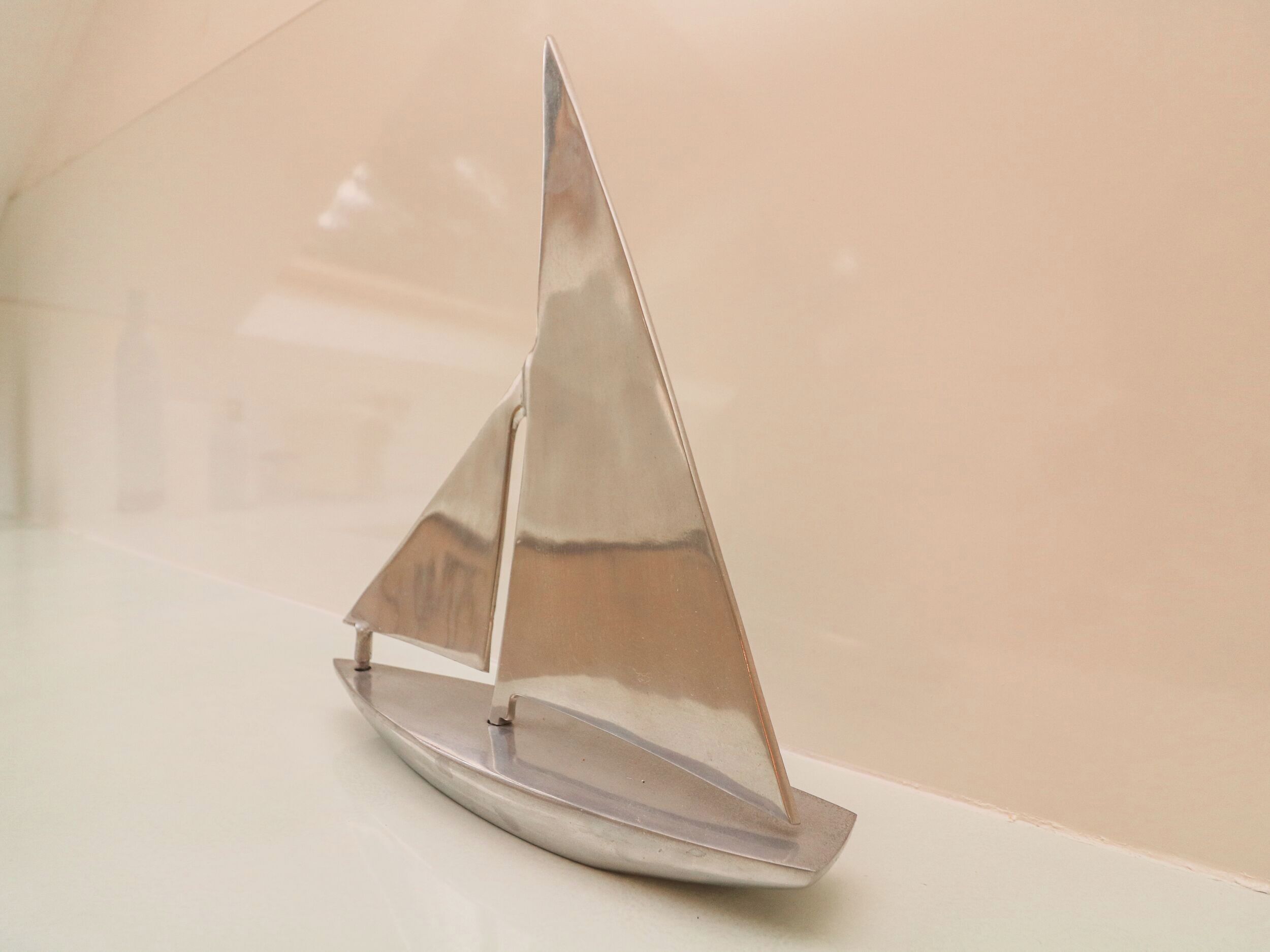 A model sailboat on a reflective surface.