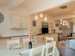 A dining area with a table set for four, a bottle of wine, and a clock on the wall. - 22 Bolt Head (Salcombe)