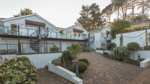 A residential building with a central courtyard, featuring a brick pathway, a glass balustrade, and various plants. - 22 Bolt Head (Salcombe)