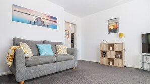 Un salon avec un canapé gris, un meuble en bois et un téléviseur.