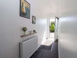 A hallway with a radiator, a doormat, a shelf with decorative items, and a door leading outside.