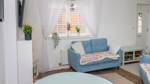 Una sala de estar con un sofá azul, un radiador blanco y una ventana con persianas.