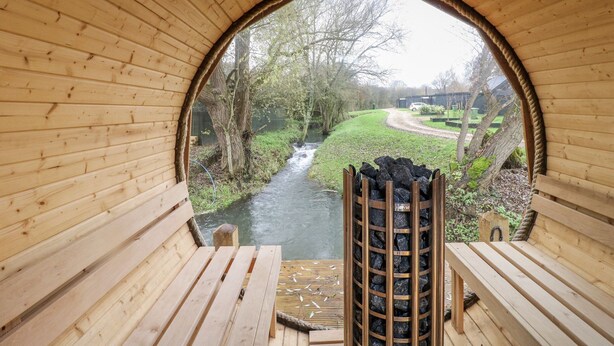 A wooden structure with a view of a river and trees. - Badger's Burrow (Oakham)