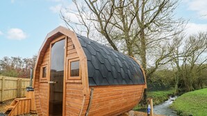 A wooden cabin with a sloped roof, a door, and a window. - Badger's Burrow (Oakham)