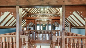 A wooden staircase with a balustrade leading to a room with a sloped ceiling and a chandelier. - The Old Chapel (Gainsborough)
