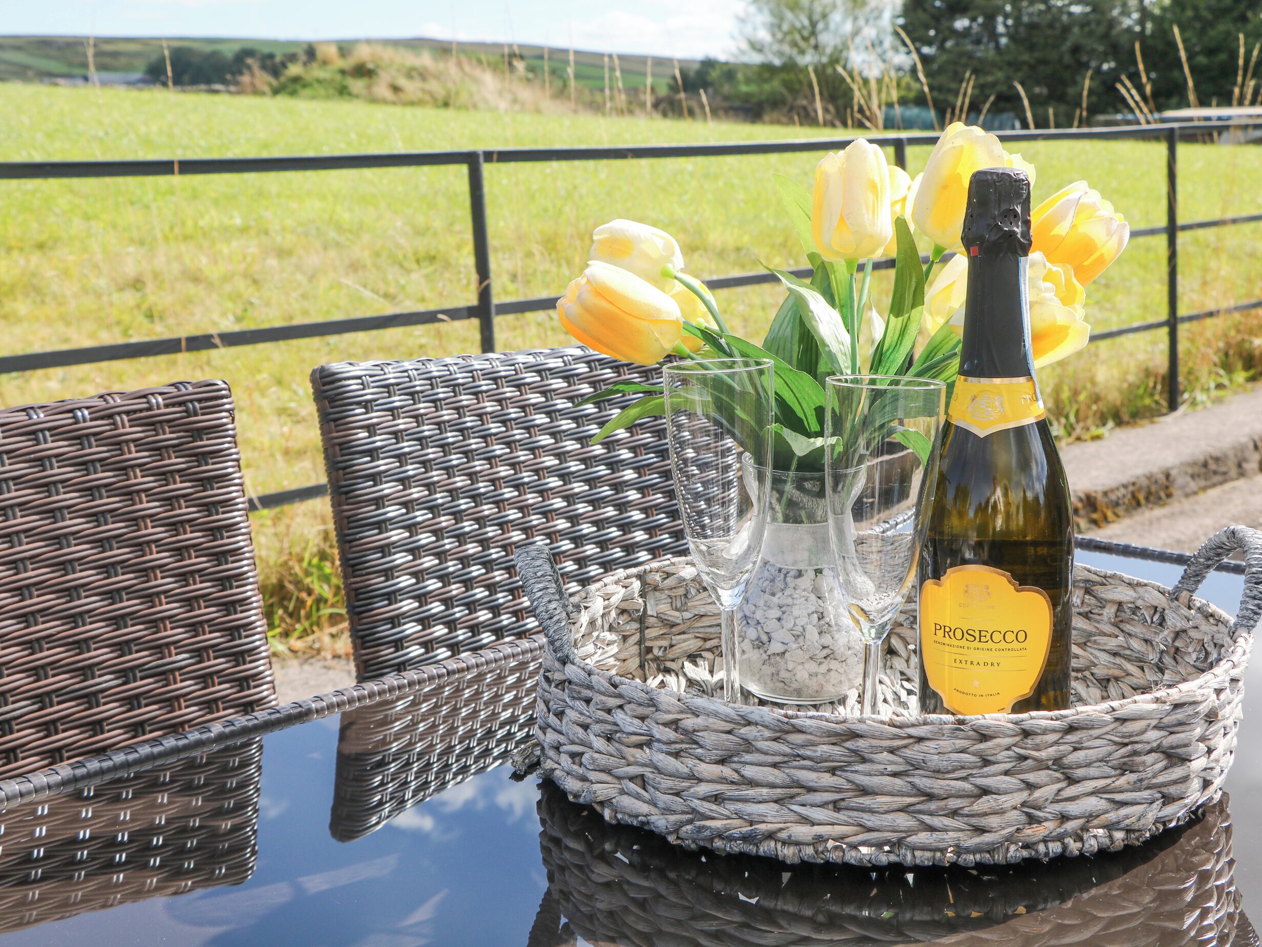 A wicker table with a bottle of Prosecco and tulips.