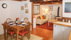 Un espace repas comprenant une table et des chaises en bois, un canapé et un coin cuisine avec une cuisinière.