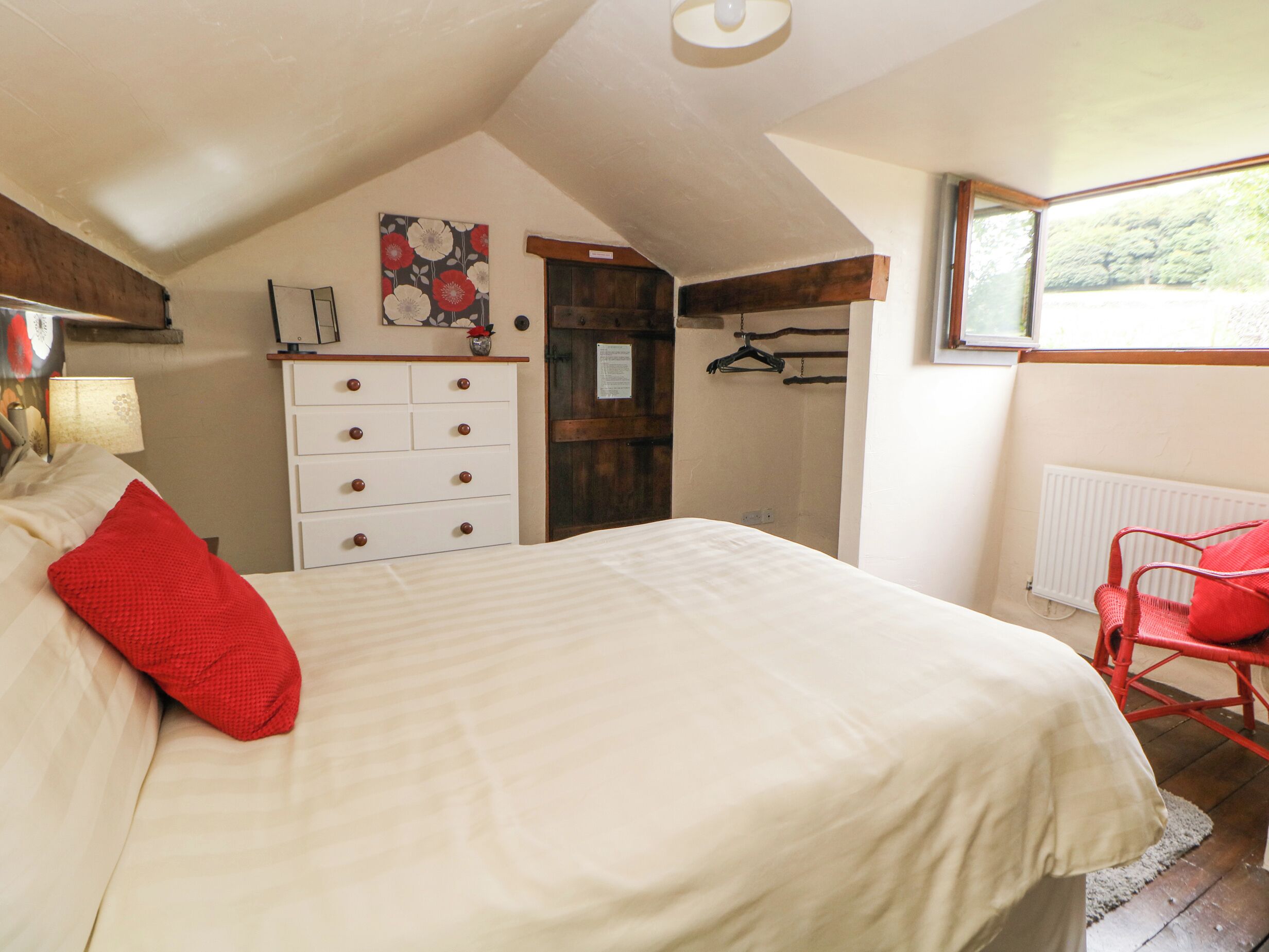 A bedroom with a bed, a dresser, a window, and a radiator.