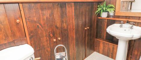 A bathroom with wooden walls, a white sink, and a toilet.
