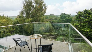 A balcony with a glass railing, two chairs, and a table. - Rushfield (Cardigan)