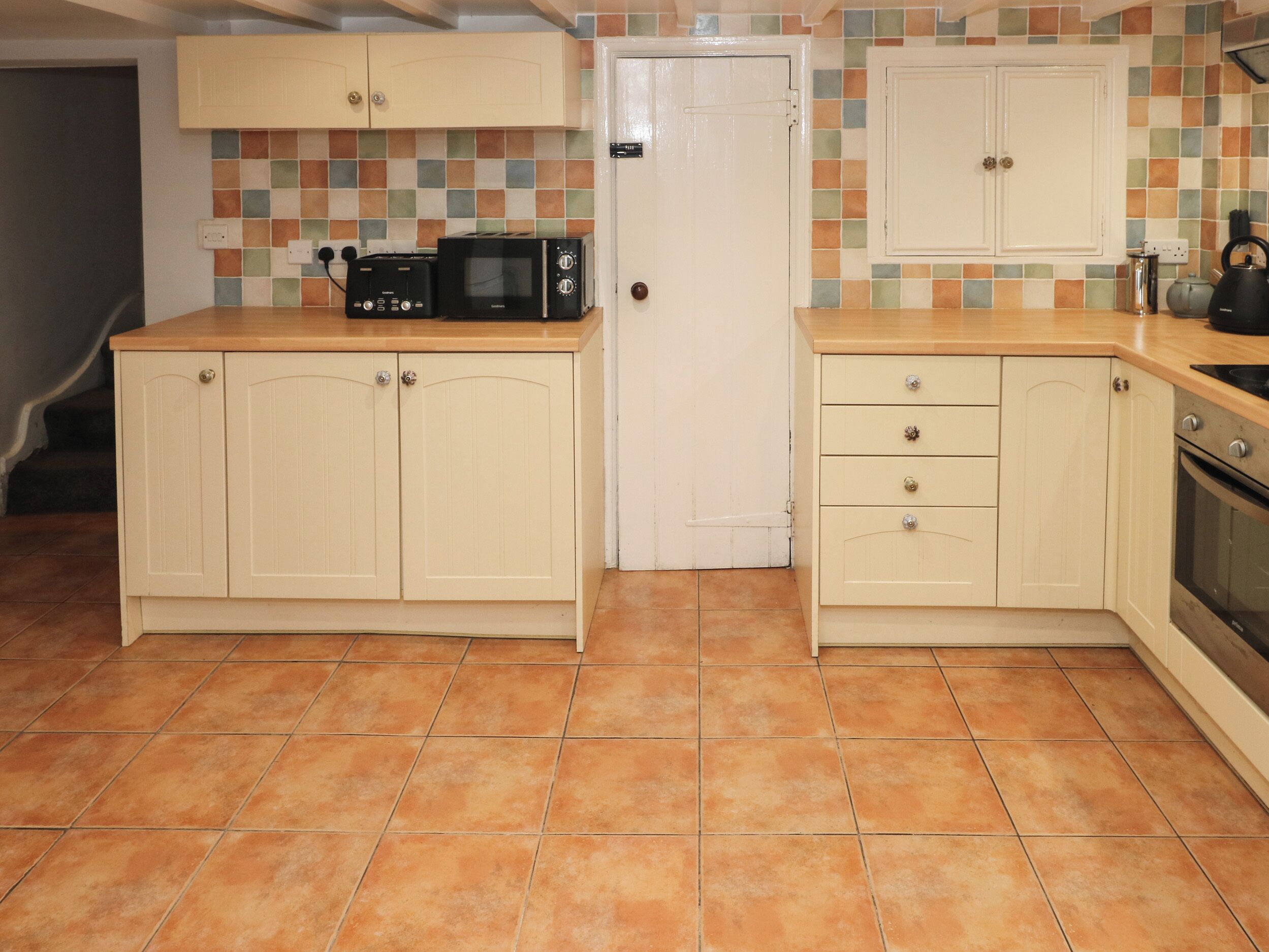 A compact kitchen with two cabinets, a microwave, and a kettle.