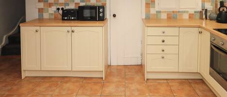 A compact kitchen with two cabinets, a microwave, and a kettle.