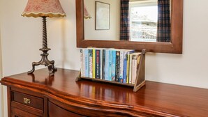 A wooden desk with a lamp, a mirror, and a bookshelf with books. - Keartons - Buttertubs (Richmond)