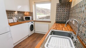 A compact kitchen with a washing machine, a microwave, and a sink with a drying rack. - Keartons - Buttertubs (Richmond)
