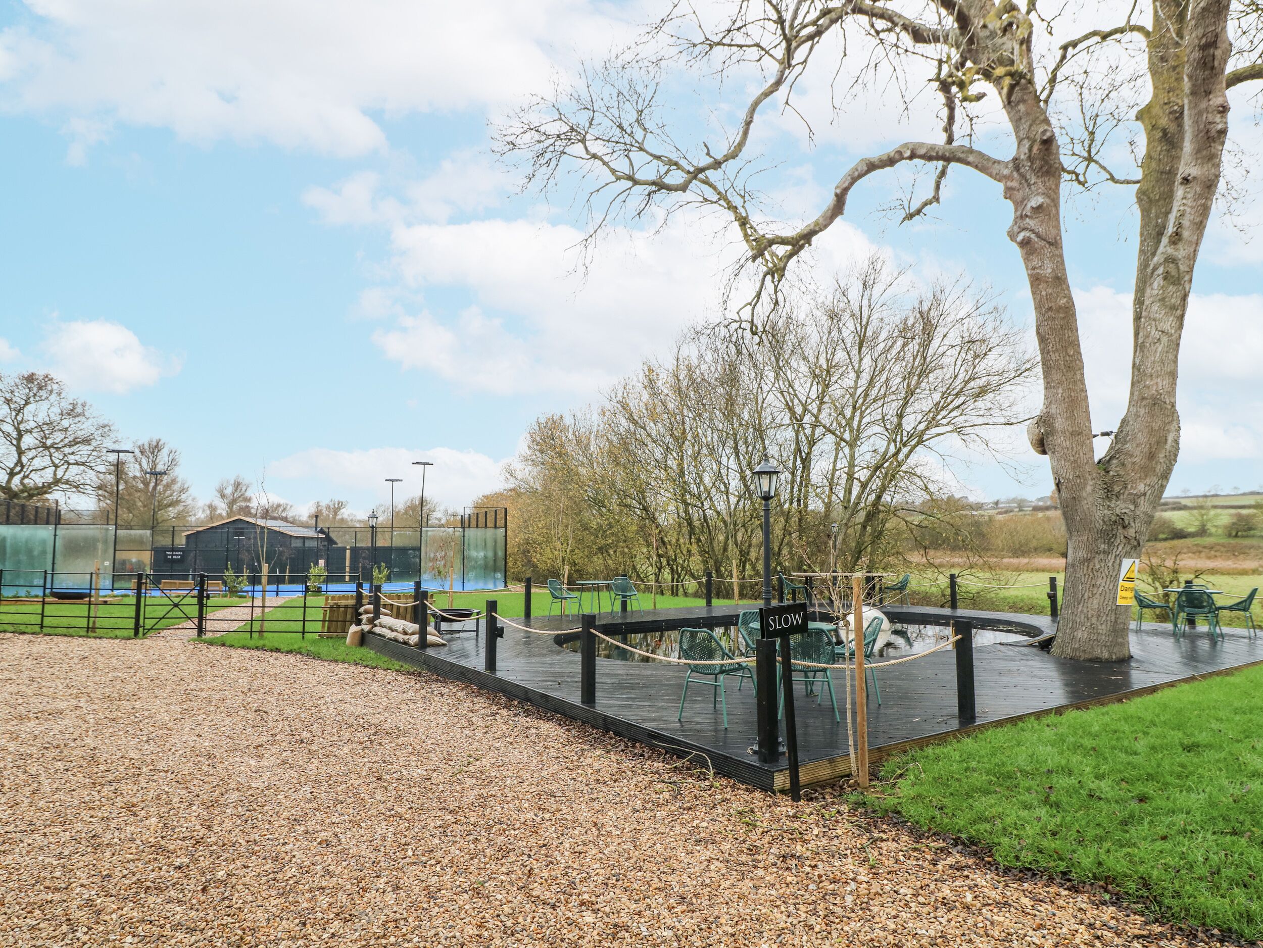 An outdoor area with a gravel path, seating area, and a stage with a 'SLOW' sign.