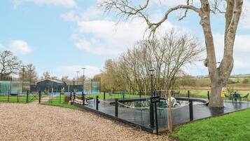 An outdoor area with a gravel path, seating area, and a stage with a 'SLOW' sign.
