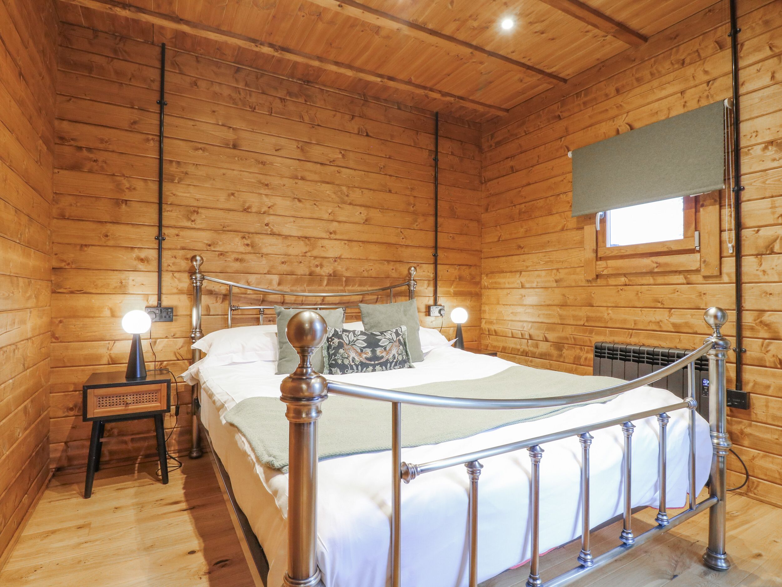 Een kamer met houten lambrisering, een bed, een nachtkastje en een raam.