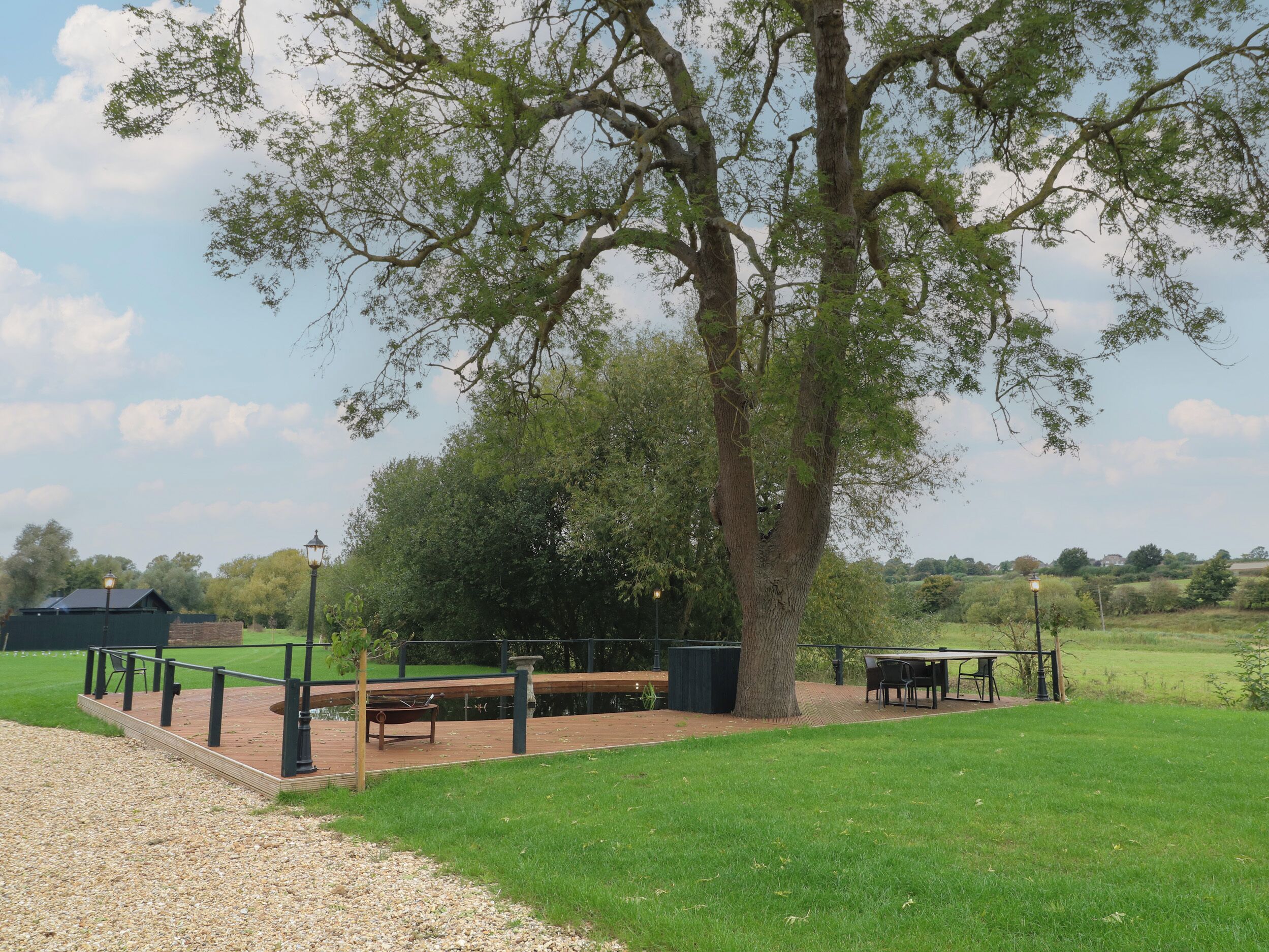 A park with a picnic area, benches, and a large tree.