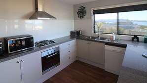 Une cuisine moderne équipée d’une cuisinière à gaz, d’un four et d’un four à micro-ondes, d’une grande fenêtre offrant une belle vue et d’un lave-vaisselle.