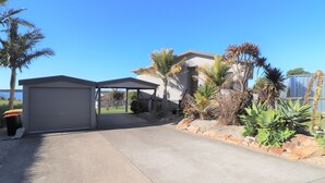 Il s’agit d’une propriété résidentielle dotée d’un garage fermé, d’une maison avec un toit en pente et d’une grande variété de plantes tropicales.