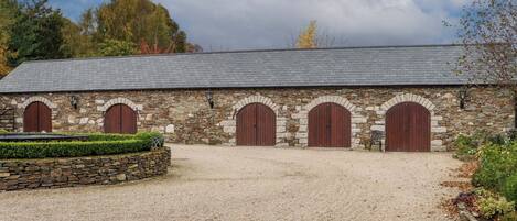 A stone building with four arched doors and a gravel driveway.