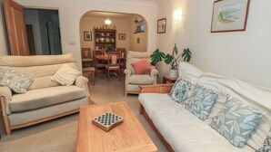 A living room with a sofa, armchair, and a wooden coffee table. - Old Harry Cottage 16 (Swanage)