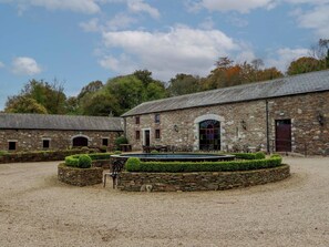 A stone building with a courtyard, a fountain, and outdoor seating. - Ballybeg Pod 1 (Ballybeg)