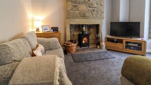 A cozy living room with a stone fireplace, a television, and a comfortable sofa. - 5 Hamilton Terrace (Harrogate)