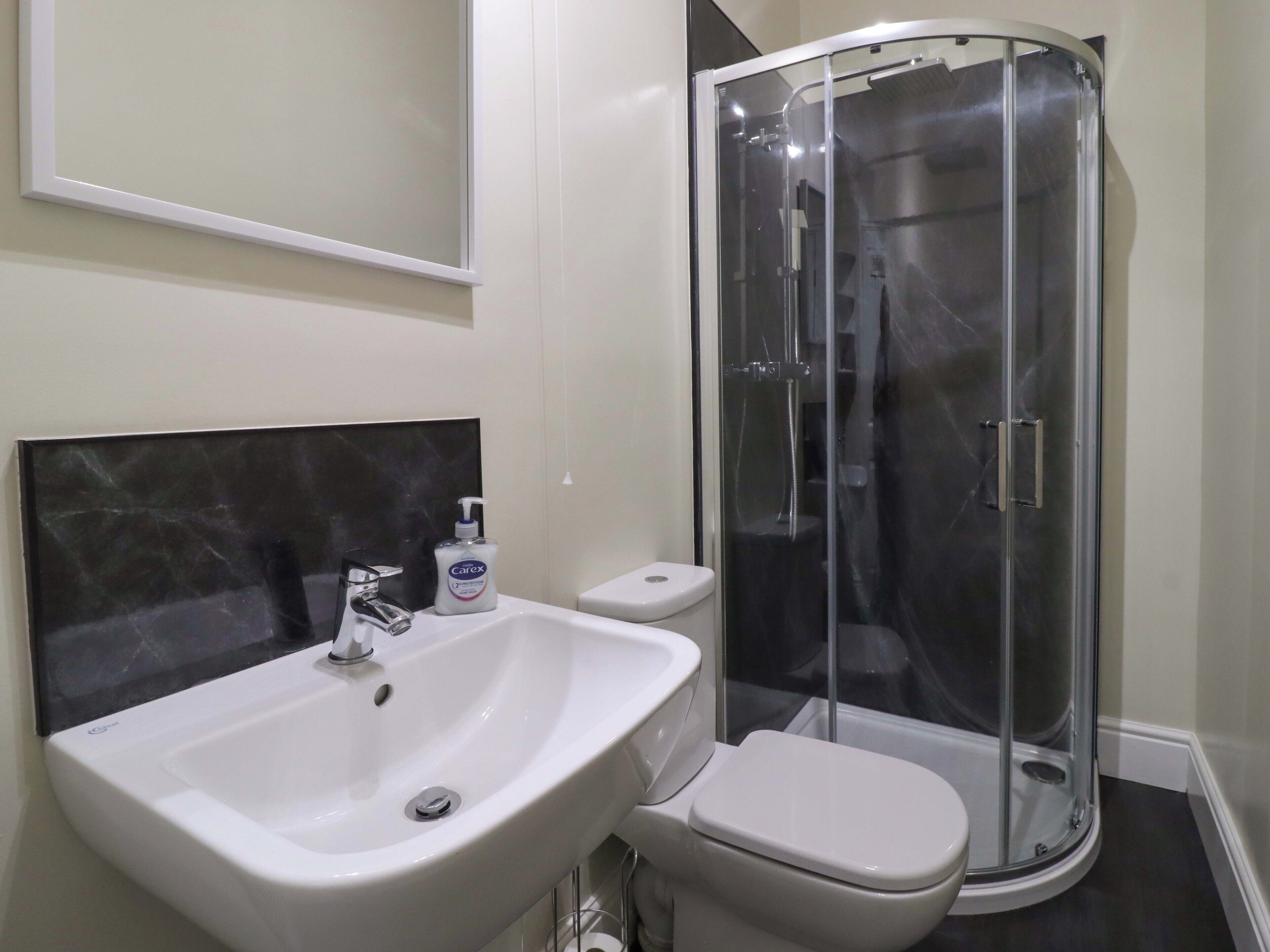 A bathroom with a white sink, a toilet, and a glass-enclosed shower.