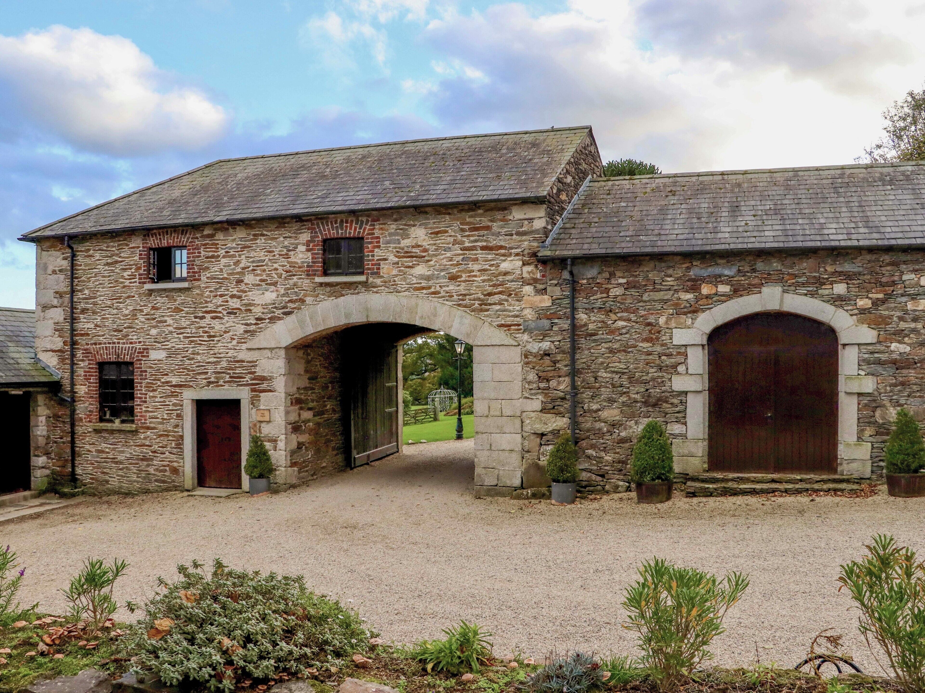 A stone building with a gravel driveway and a large wooden door.