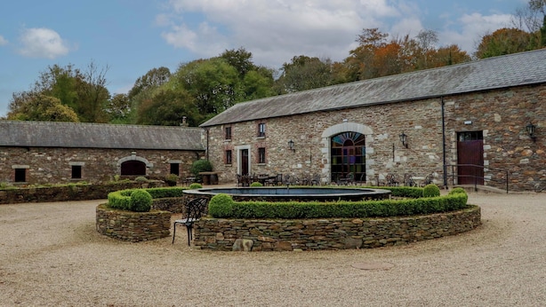 A stone building with a courtyard, a fountain, and outdoor seating. - Ballybeg Pod 6 (Ballybeg)