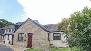 A stone house with a red door, a small front yard, and a garden with various plants. - Chy Lowena (Falmouth)