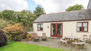 A house with a tiled patio, a wooden table, and chairs. - Chy Lowena (Falmouth)