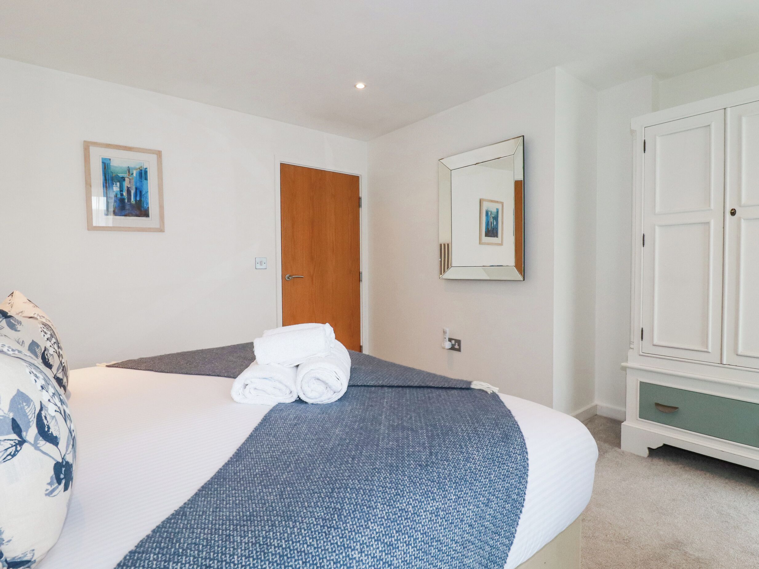 Une chambre d’hôtel avec un lit, une porte en bois, un miroir et une armoire.