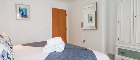 Une chambre d’hôtel avec un lit, une porte en bois, un miroir et une armoire.