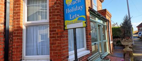 A brick building with a sign advertising 'Walton Beach Holiday Lets'.