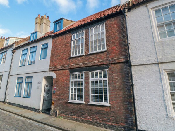 A row of traditional brick and plaster buildings with uniform window designs and a cobblestone street.
