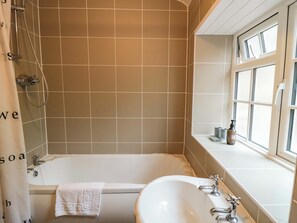 A bathroom with a bathtub, a sink, and a window. - Brewers Cottage (Pickering)