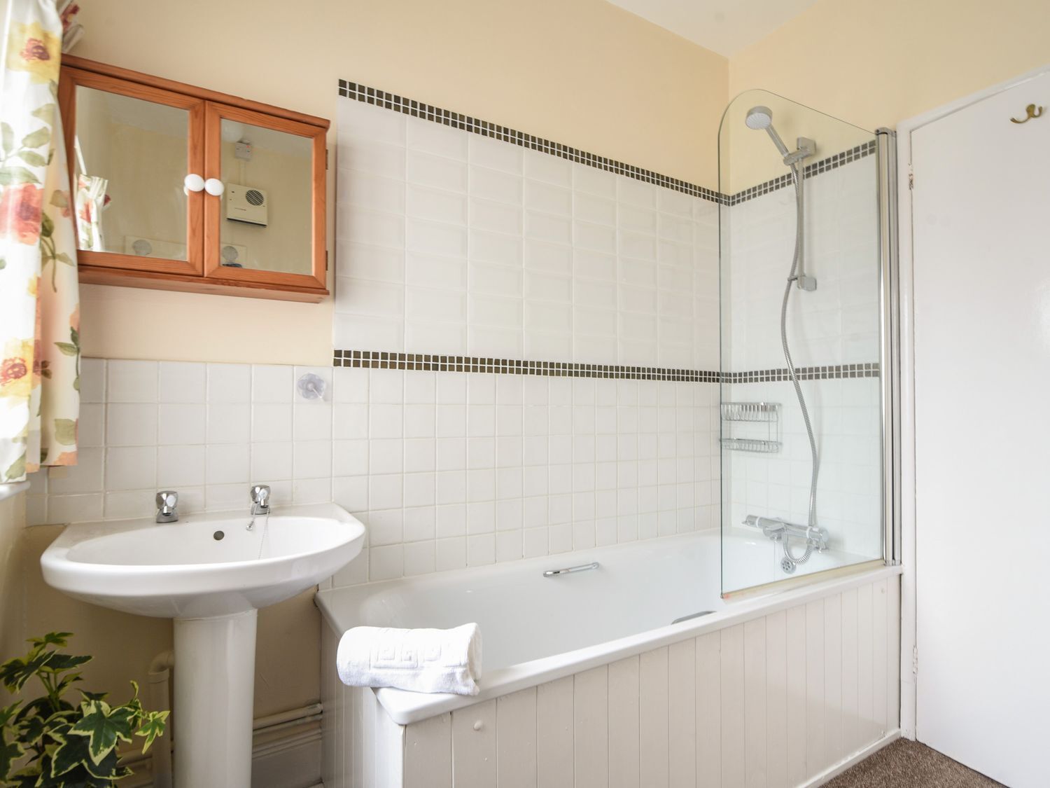 A bathroom with a white sink, a bathtub, a glass shower enclosure, and a mirror above the sink.