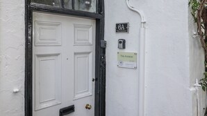 Une porte blanche avec un cadre noir, une petite plaque au-dessus indiquant « 6A, The Annexe », et une autre plaque en dessous portant le même nom et un numéro de référence.