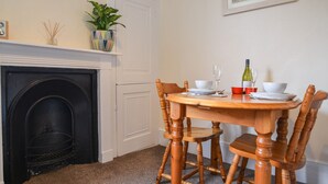 Un coin repas avec une cheminée, une table dressée pour deux personnes et un tableau accroché au mur.