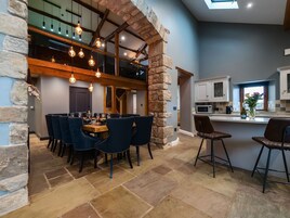 Una cocina moderna con un arco de piedra, un comedor con techo alto y luces colgantes, y vista al nivel superior.