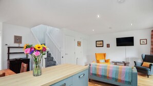 A modern living room with a sofa, a television, and a staircase. - 26 Strathtay Lodges (Aberfeldy)