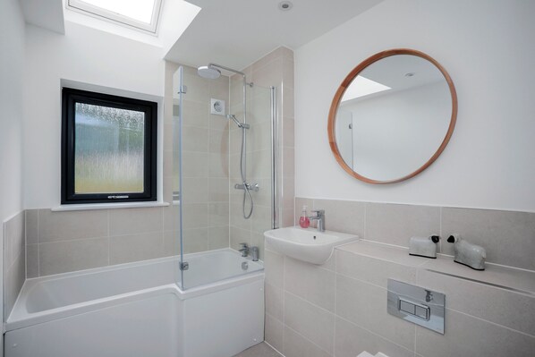 A modern bathroom with a glass-enclosed shower, a freestanding bathtub, a sink, and a round mirror on the wall. - 26 Strathtay Lodges (Aberfeldy)