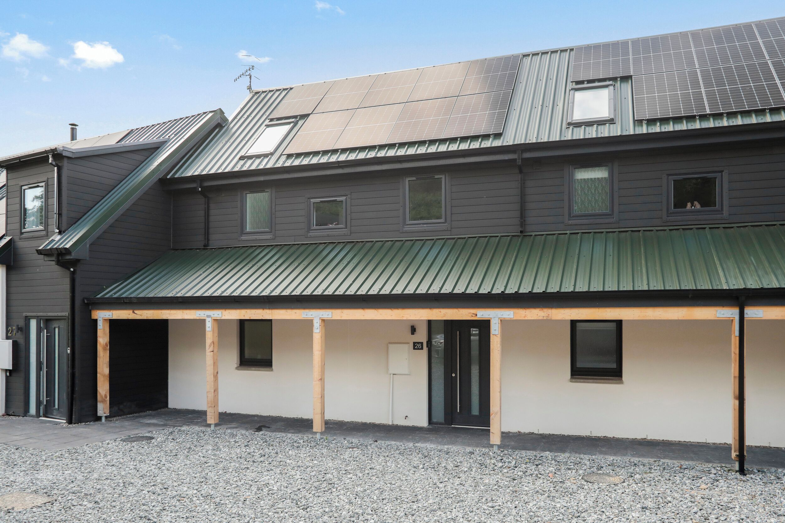 A building with a covered outdoor area, multiple windows, and a metal roof.